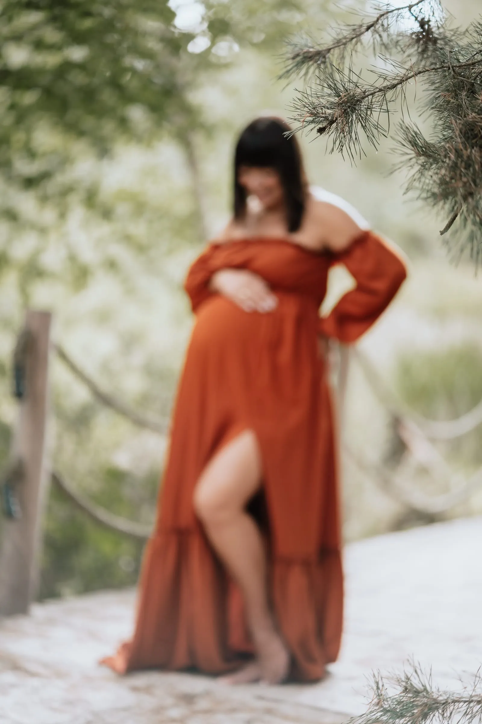 Schwangere im rostroten Kleid zwischen Bäumen