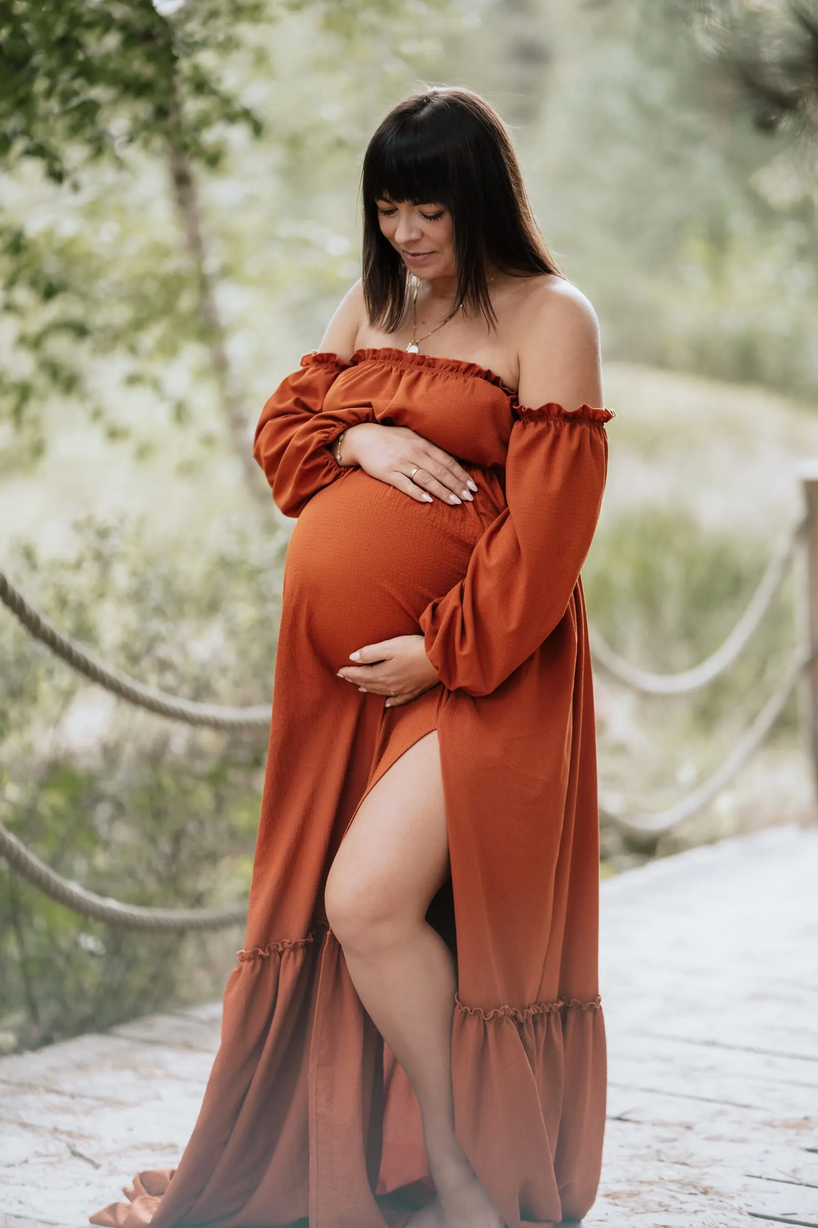Schwangere im rostroten Kleid, die Hand am Bauch