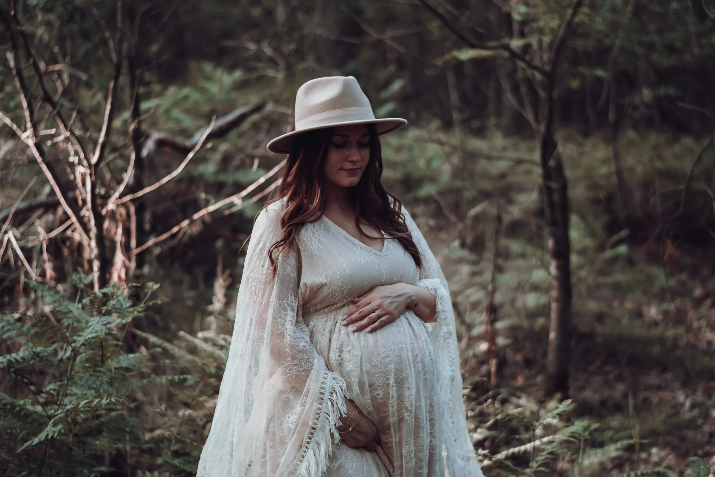 Die Schwangere mit Hut im Spitzenkleid, die Hände am Bauch