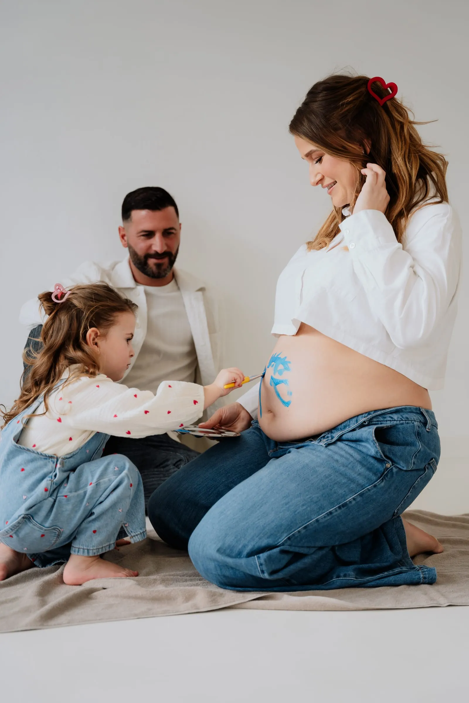 Die Tochter beugt sich über den Babybauch ihrer Mutter