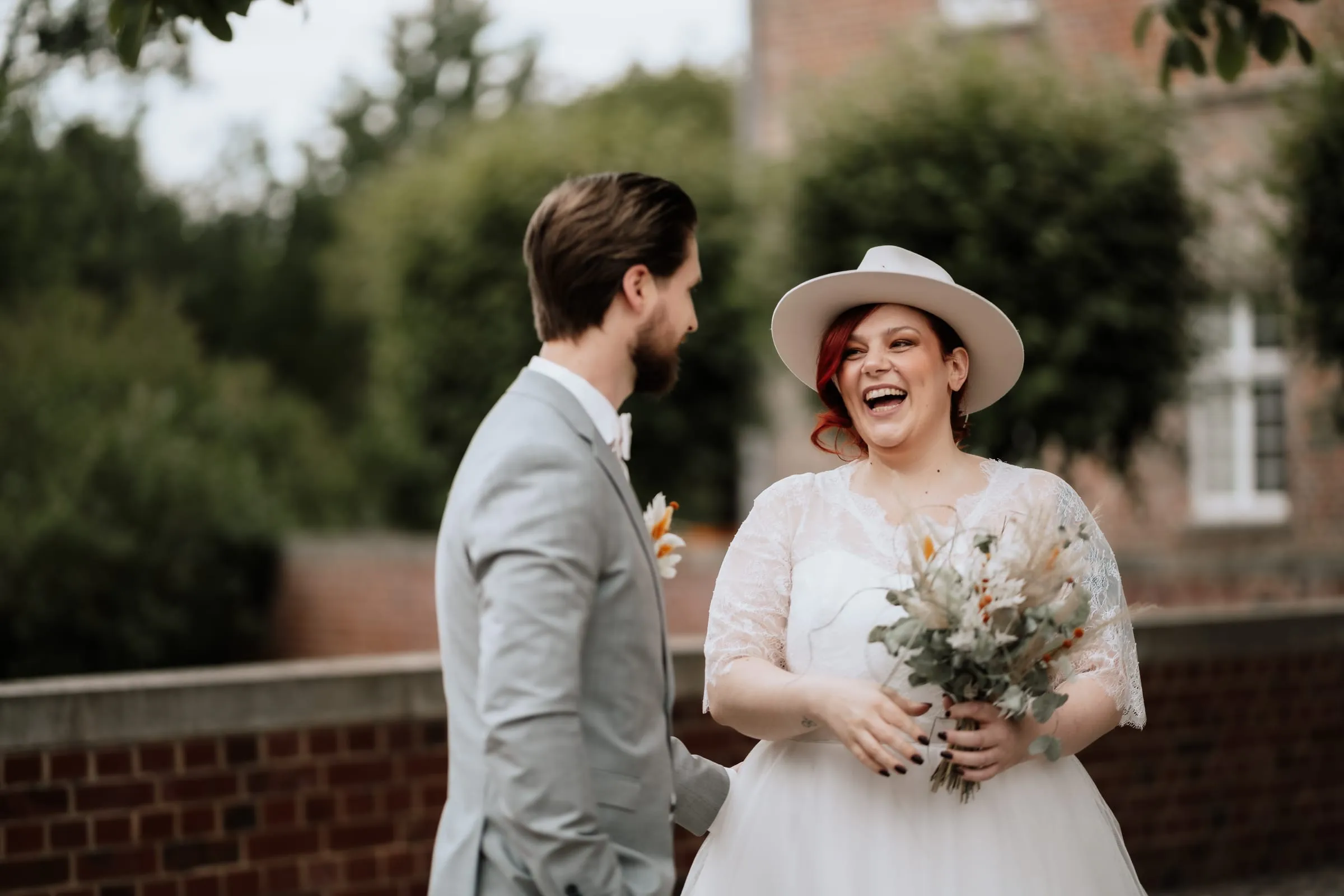 Das Paar lacht sich an, im Rücken das alte Backsteingebäude