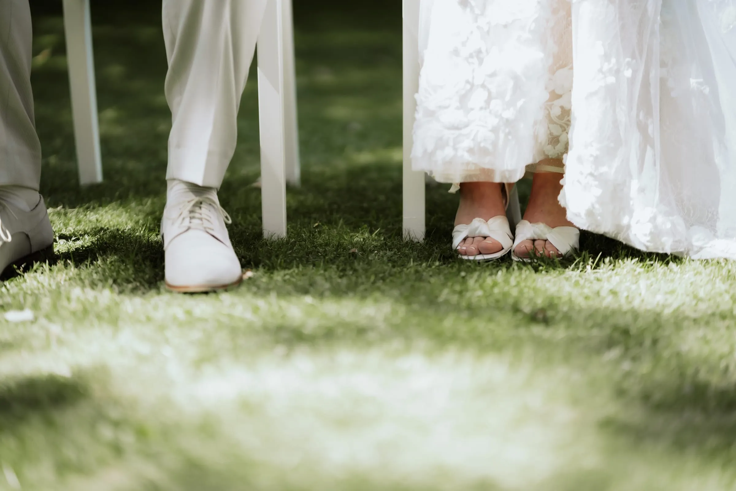 Die Füße des Paares im Gras, er in Sneakern, sie in Sandalen