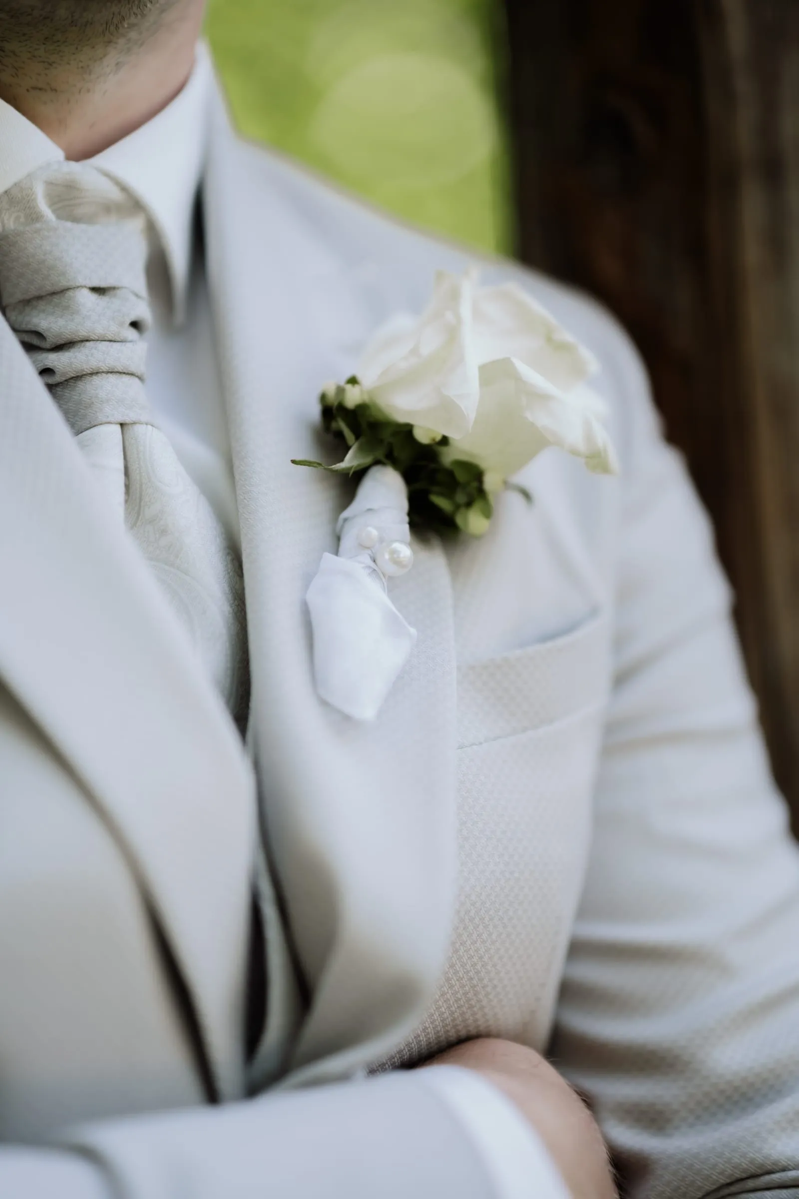 Ihre Hand am Revers, daneben die Ansteckblume