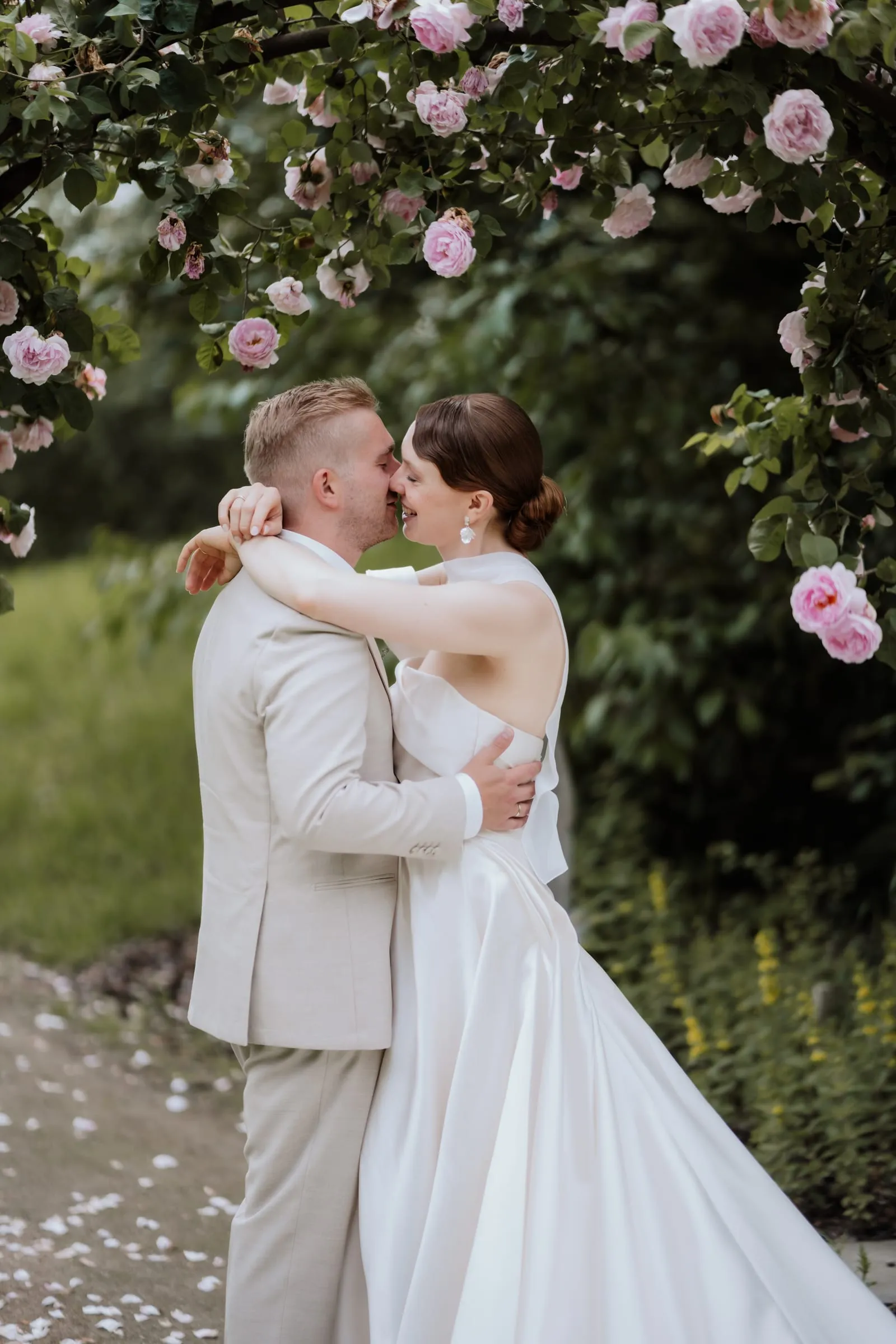 Das Paar küsst sich unter dem Rosenbogen