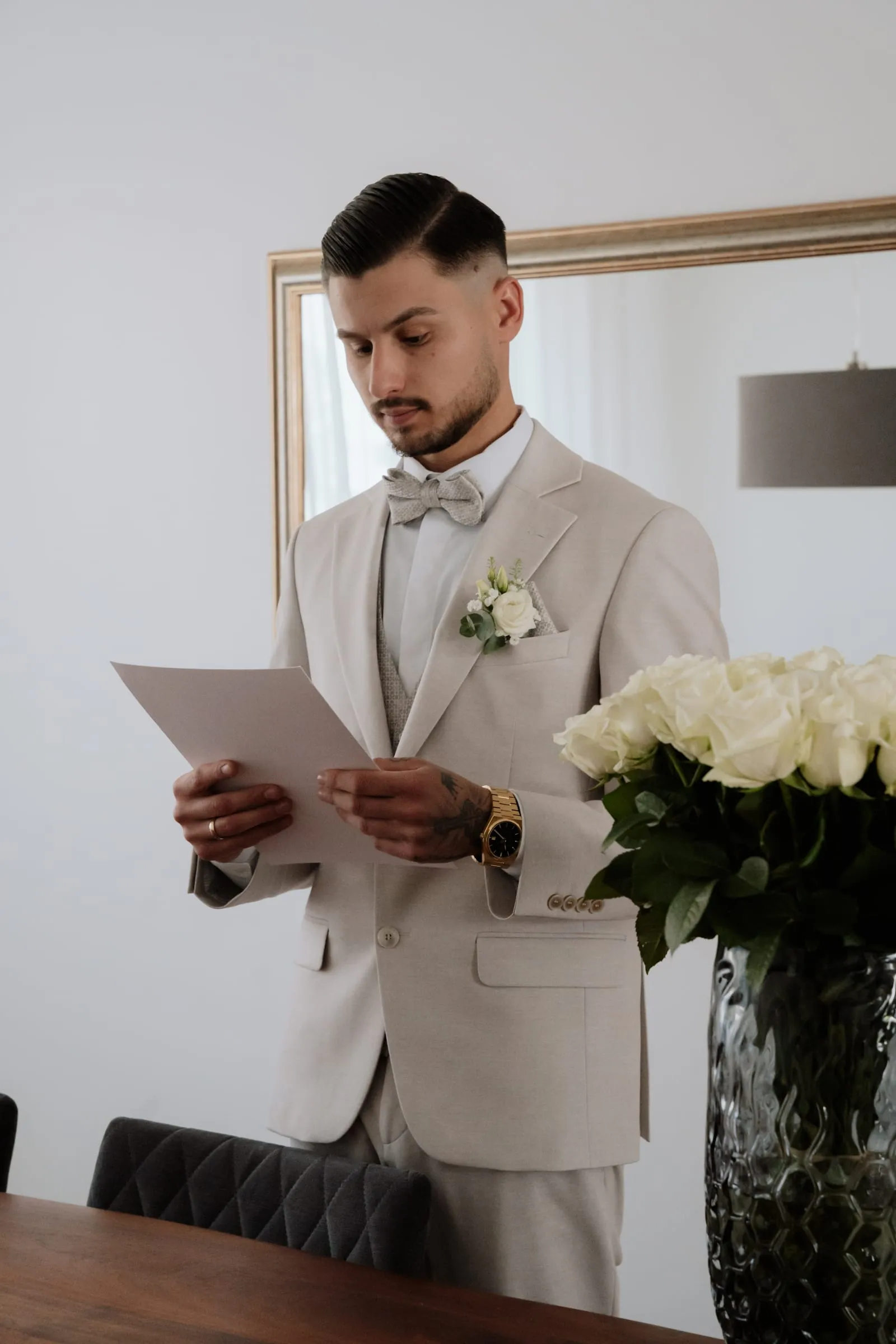 Der Bräutigam liest einen Brief, daneben weiße Rosen