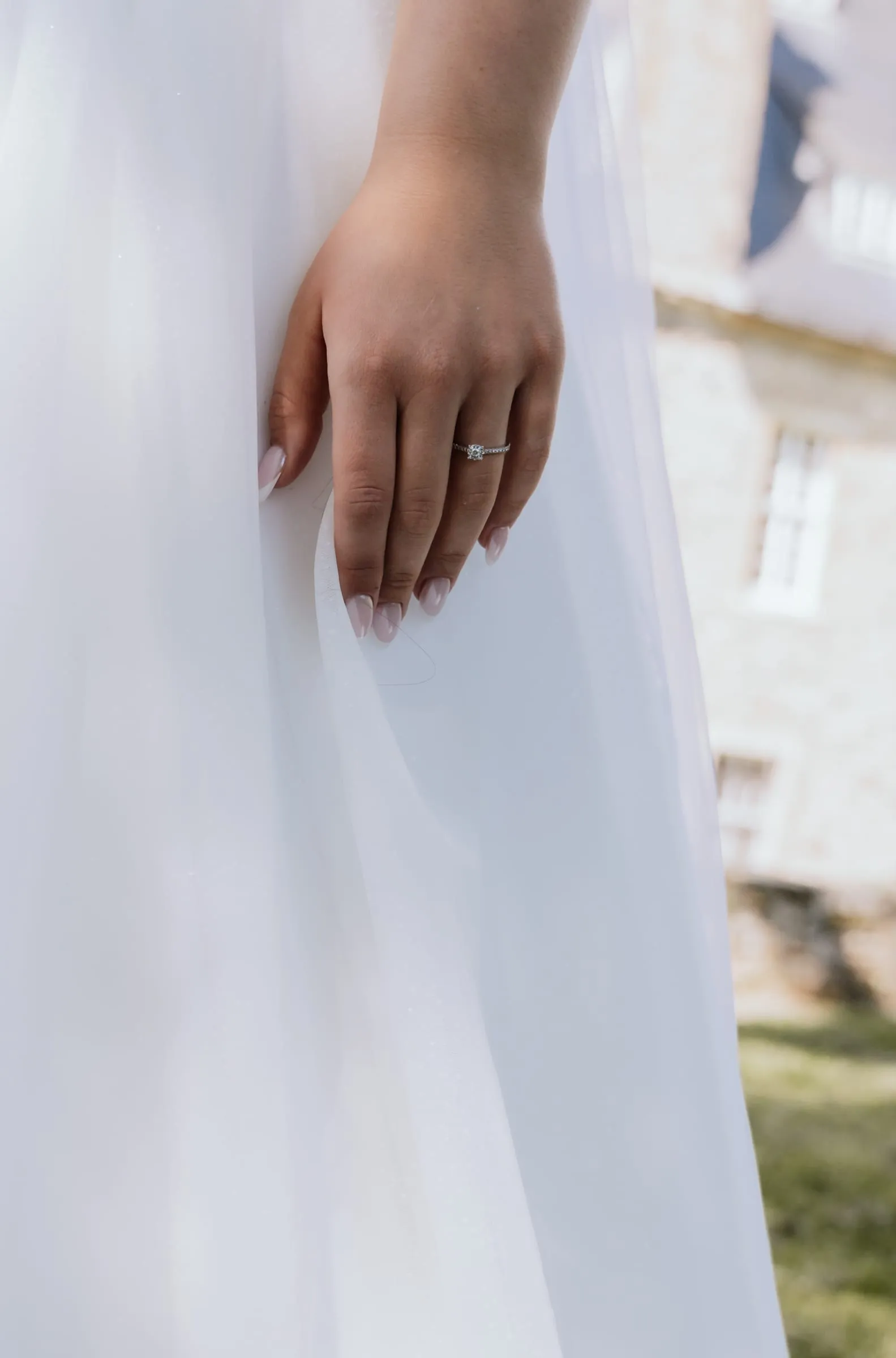 Ihre Hand mit dem Ring am Tüllkleid