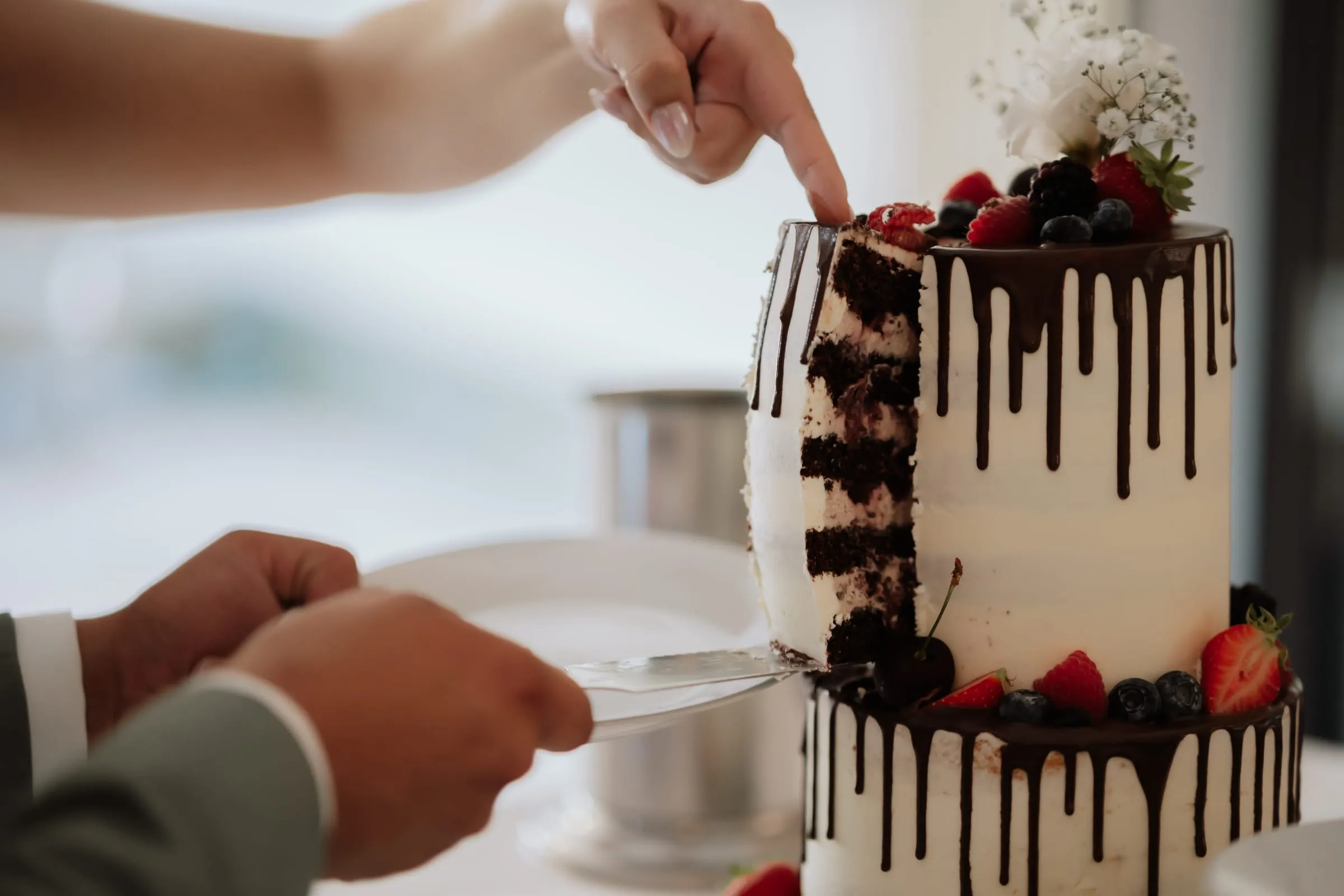 Anschnitt der Hochzeitstorte mit Schokoglasur und Erdbeeren