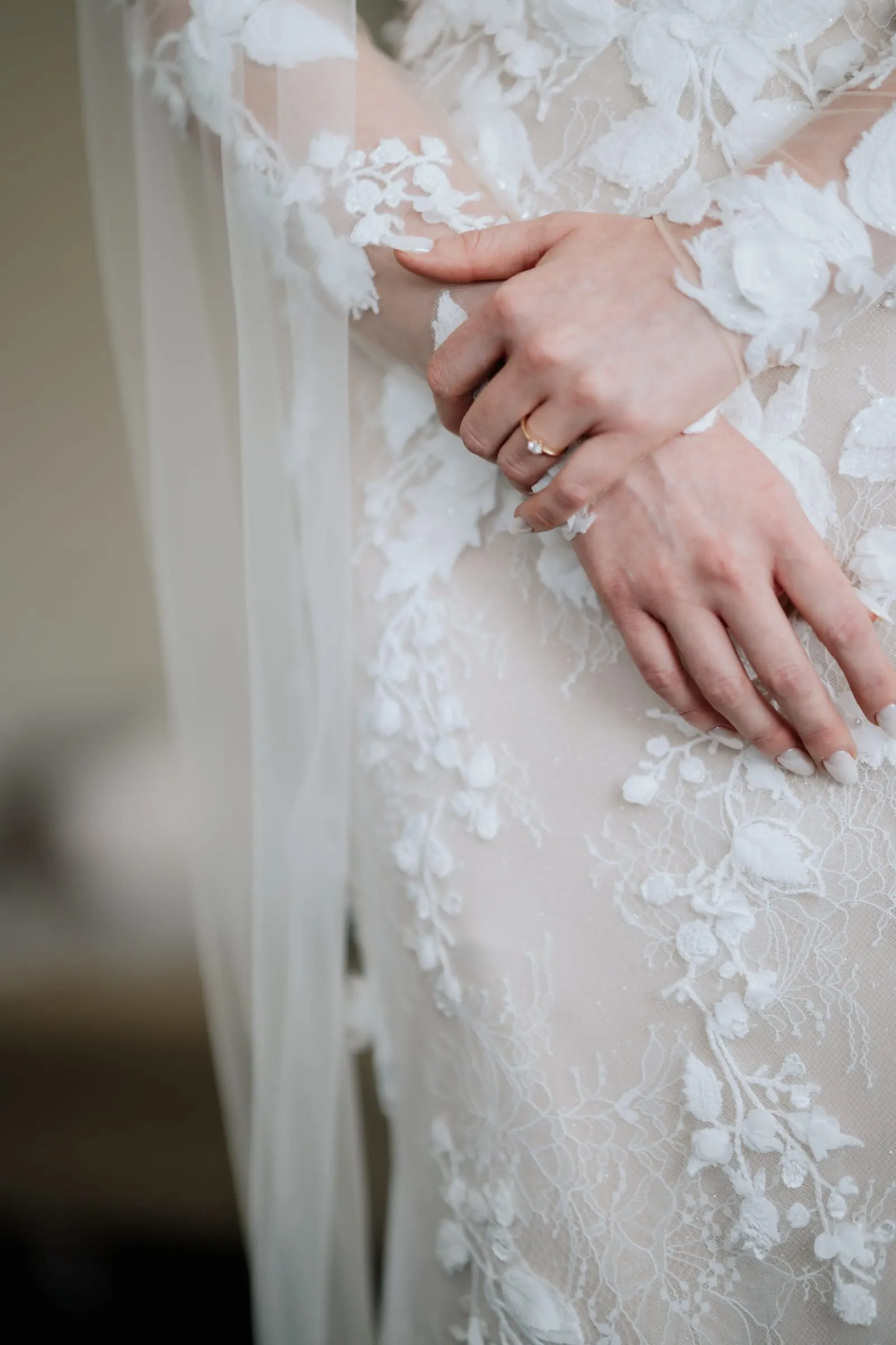 Ihre Hand mit Ring auf dem Spitzenärmel