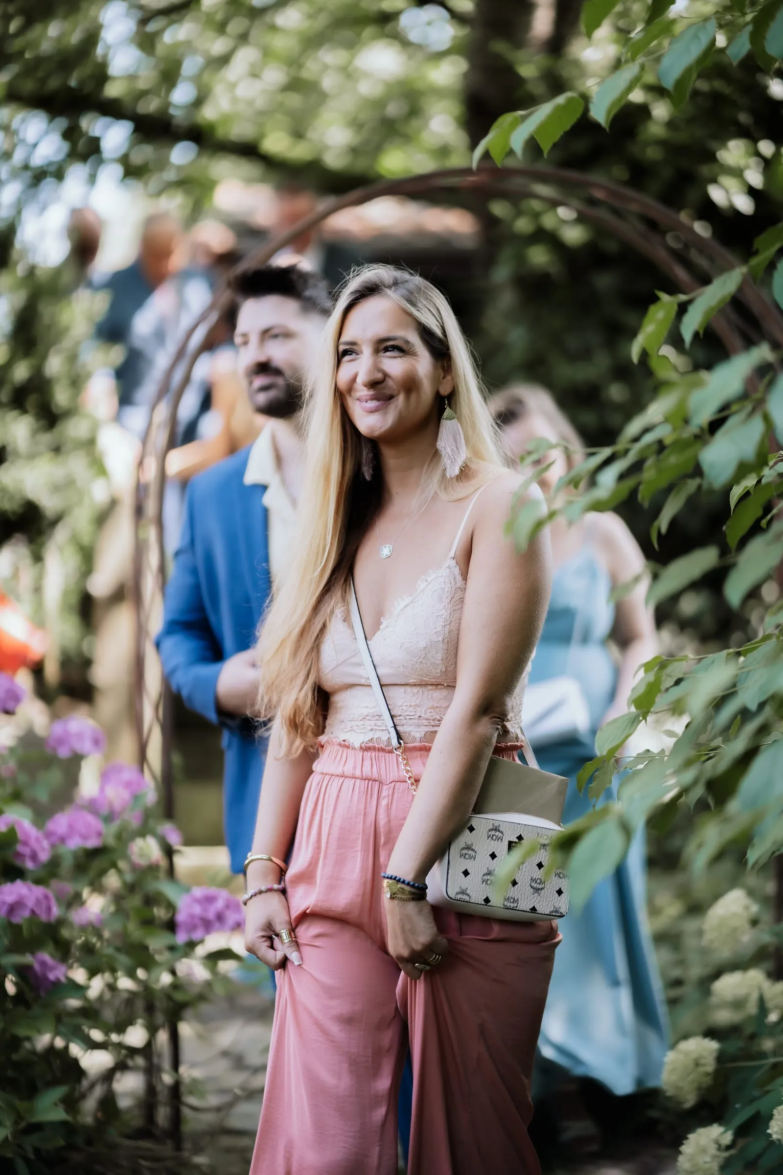 Ein Gast in Rosa wartet zwischen Blumen auf die Trauung