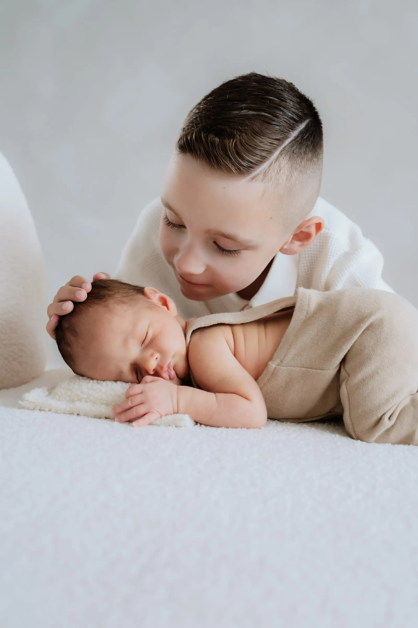 Der große Bruder lächelt neben dem schlafenden Neugeborenen