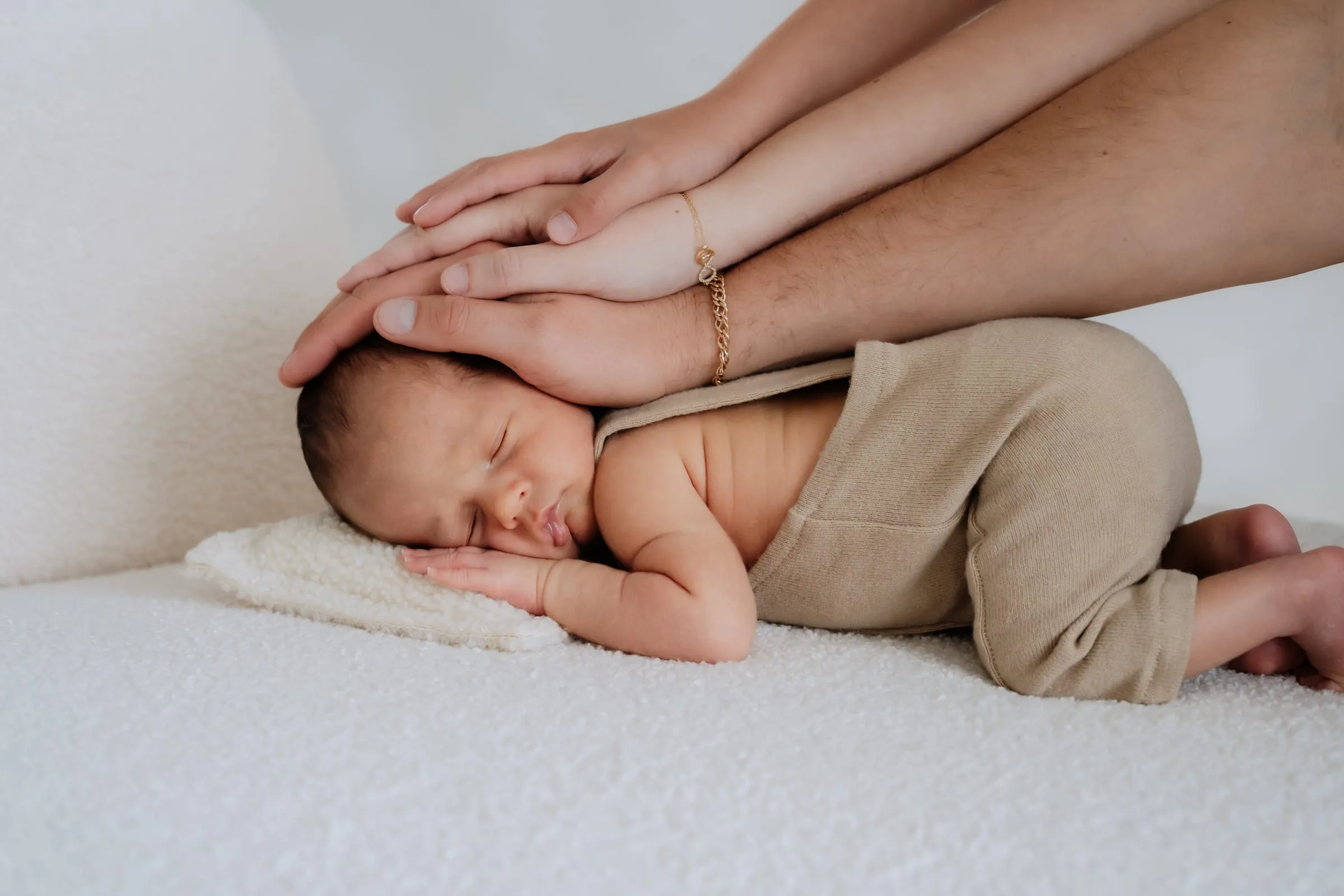 Die Hände der Eltern liegen schützend um ihr schlafendes Baby