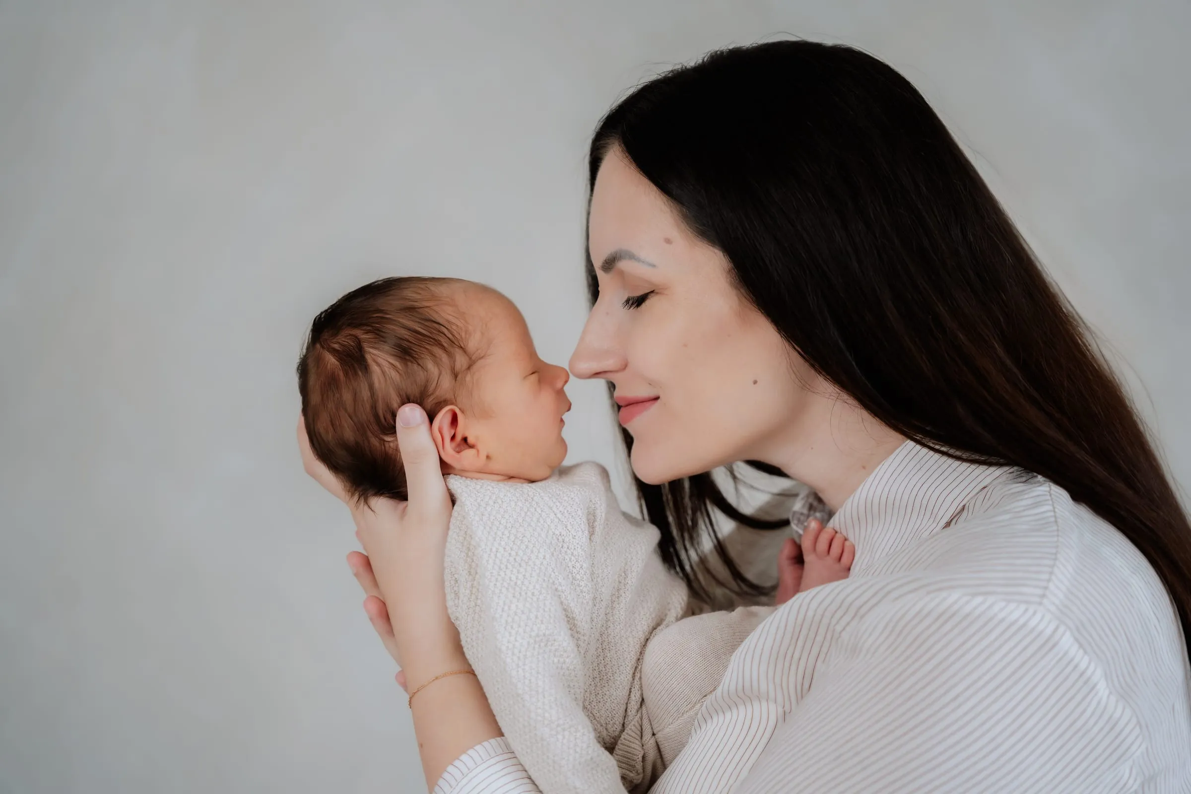 Die Mutter hält ihr Neugeborenes Nase an Nase vor sich