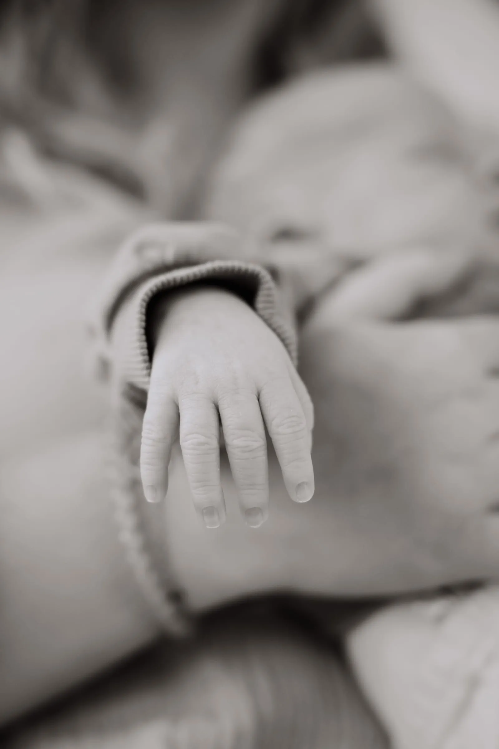 Die geöffnete Hand des Neugeborenen auf einer weichen Decke