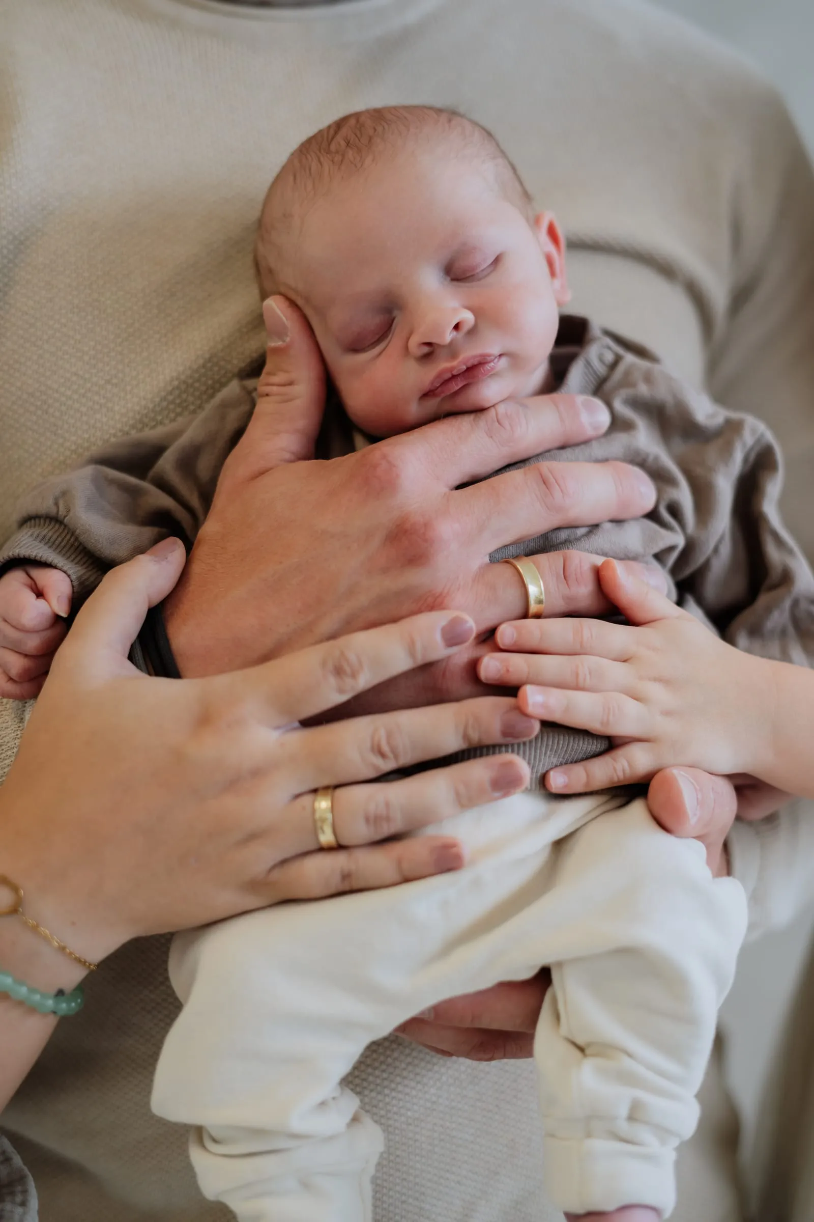Das Baby schläft in den Armen seiner Mutter, eine Hand am Köpfchen