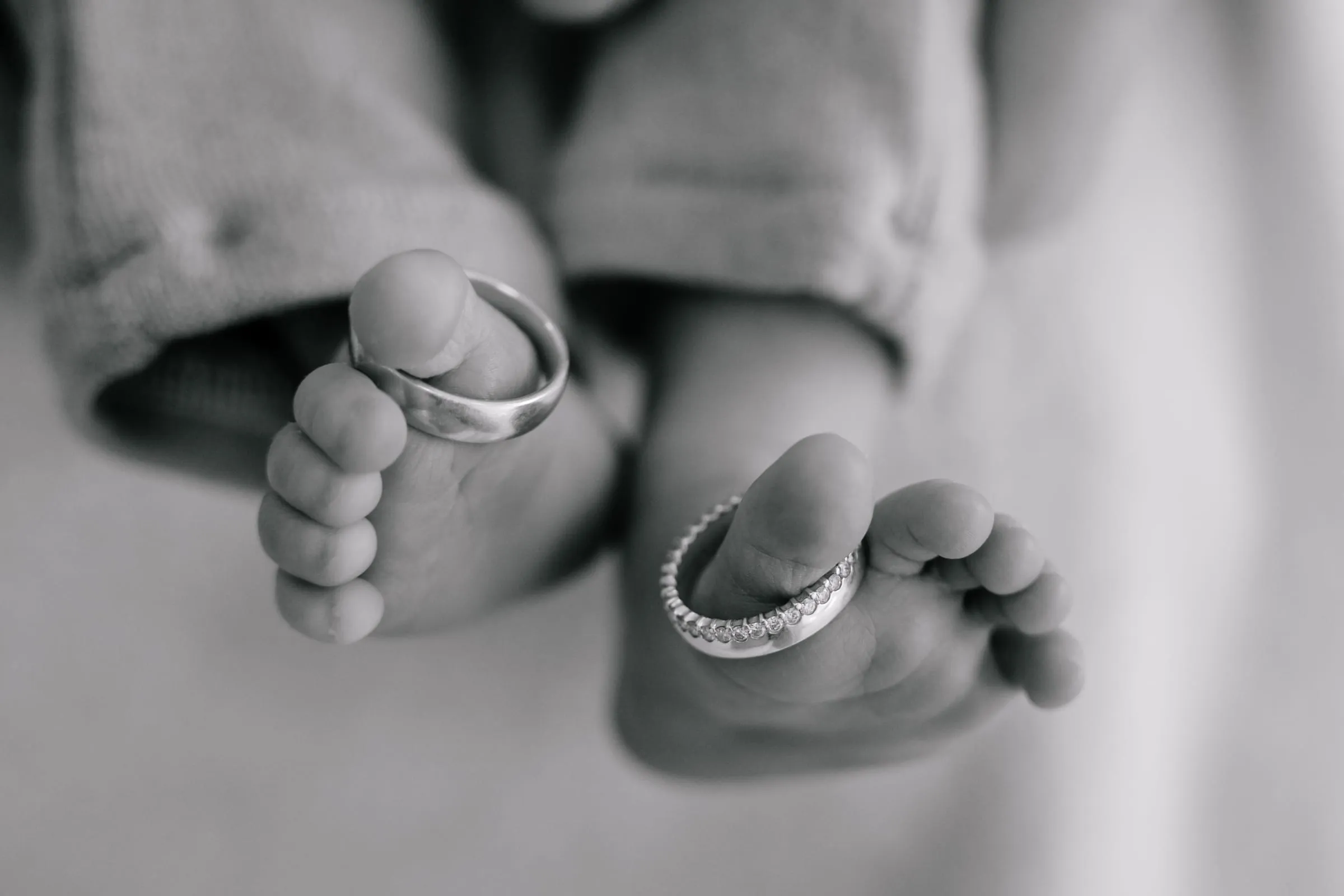 Die Eheringe der Eltern an den winzigen Zehen des Babys, in Schwarzweiß