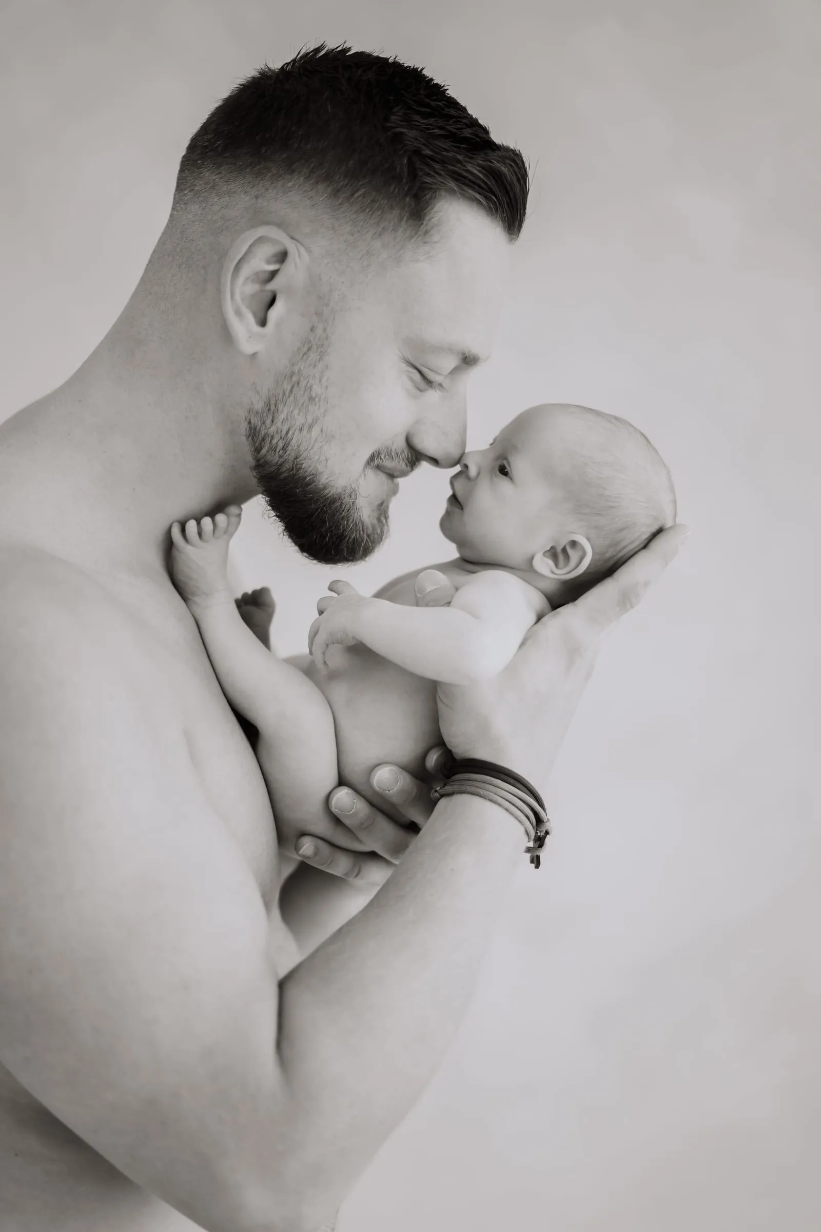 Der Vater hält sein Neugeborenes Nase an Nase, in Schwarzweiß